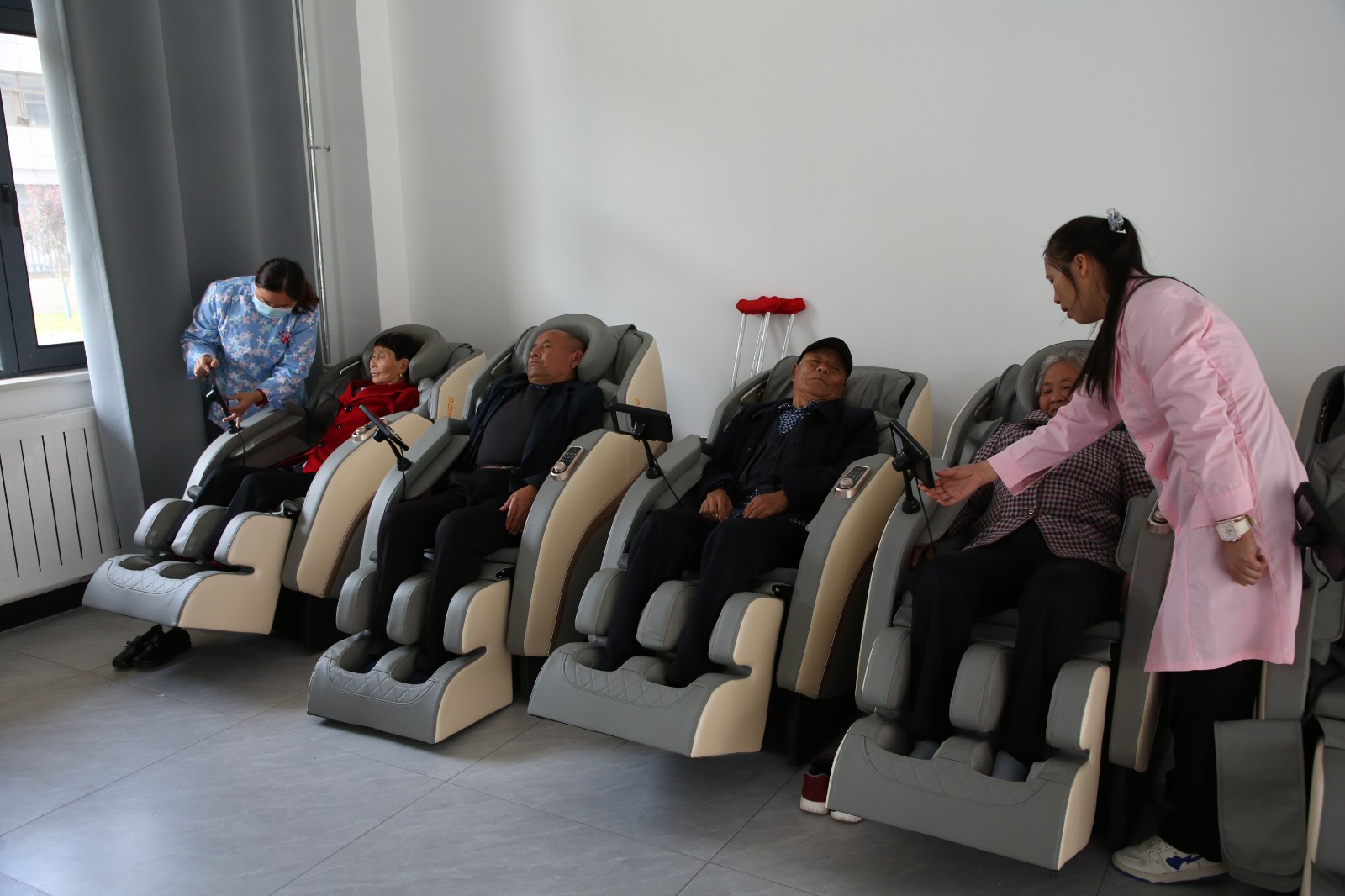 几位老人正在护理人员照顾下坐在按摩椅上按摩